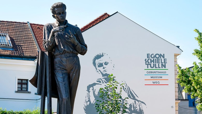 Egon Schiele Museum, © Egon Schiele Museum, Daniela Holzer Statue vor dem Egon Schiele Museum in Tulln mit Wandbild im Hintergrund.