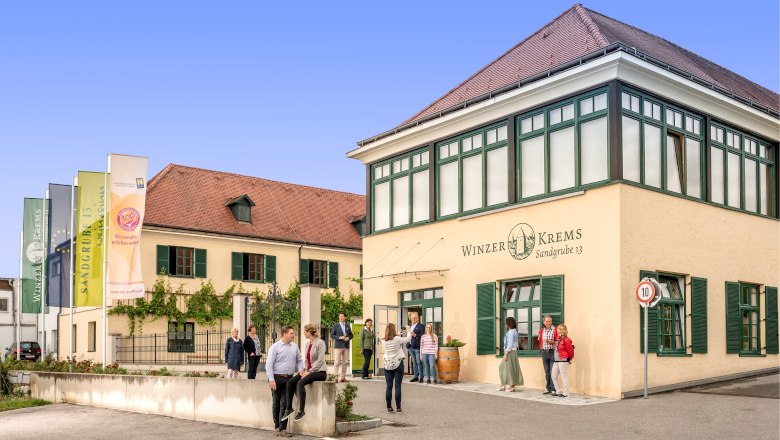 Winzer Krems - Weinerlebnis „SANDGRUBE 13 WEIN.SINN“, © Robert Herbst Gebäude von Winzer Krems mit Menschen davor.
