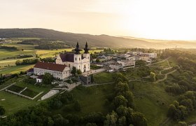 Luftaufnahme von Maria Taferl mit Kirche und umliegender Landschaft bei Sonnenuntergang.
