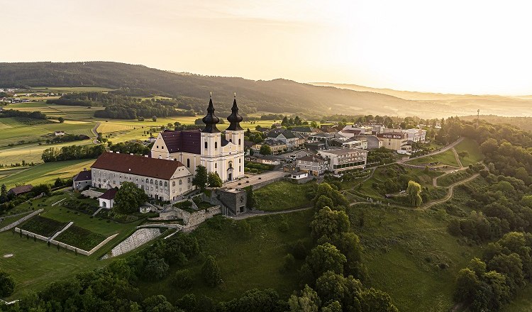 Luftaufnahme von Maria Taferl mit Kirche und umliegender Landschaft bei Sonnenuntergang.