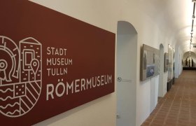 Innenansicht des Römermuseums Tulln mit Ausstellungsstücken und Infotafeln.